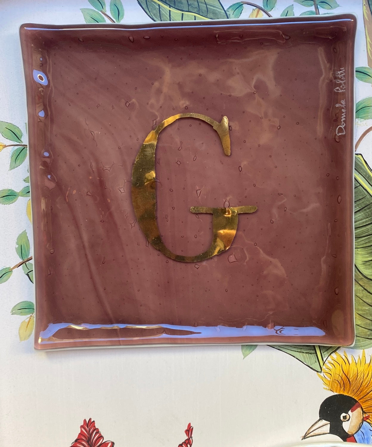 Square pocket tray in fused glass in plum letter G by Daniela Poletti. Orderable